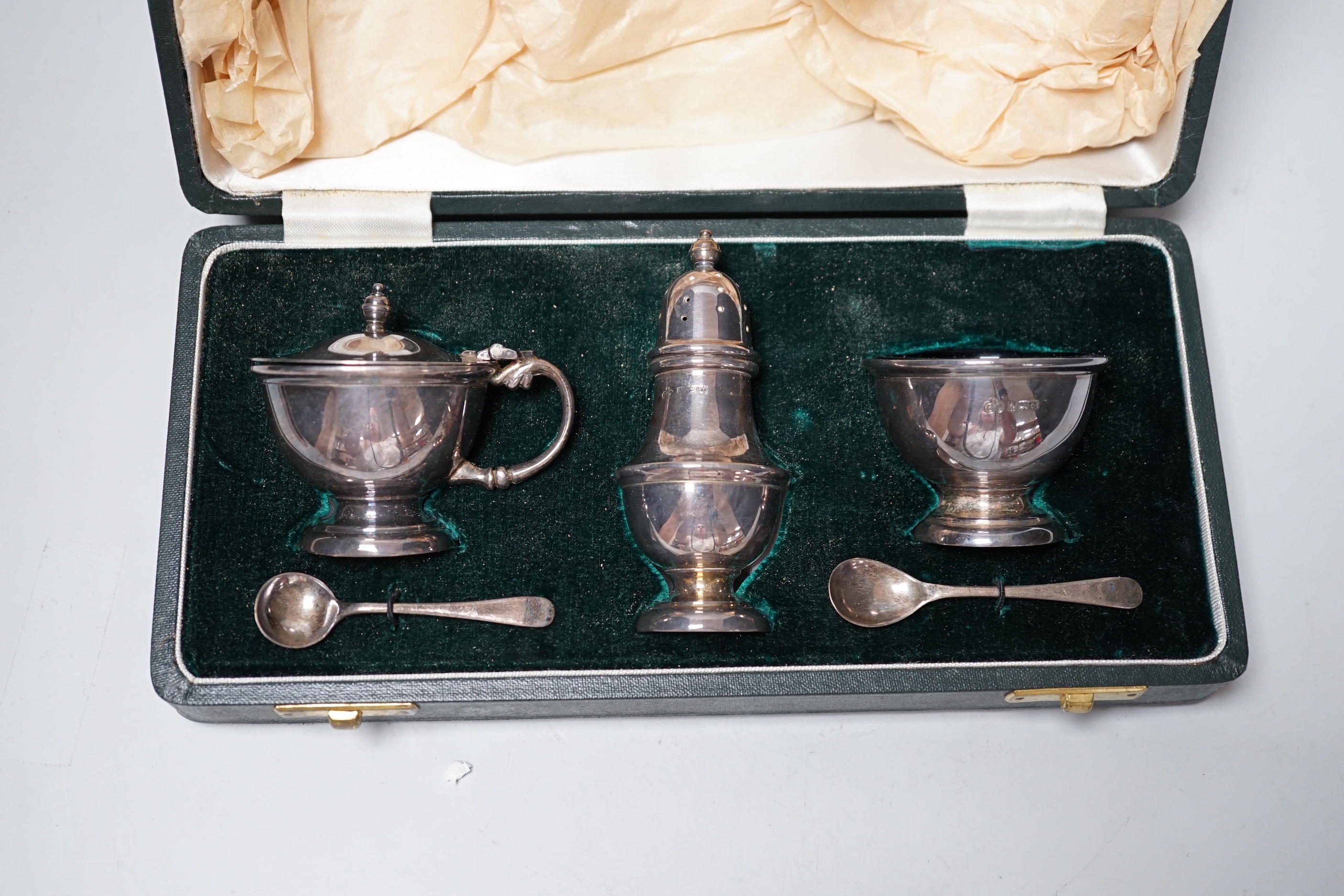 An Elizabeth II cased silver three piece condiment set, Elkington & Co, Birmingham, 1963 and two silver condiment spoons.